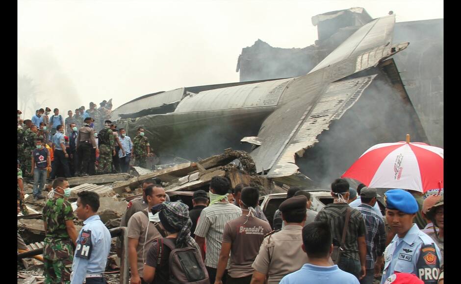 Military personnel inspect the wreckage of an Air Force cargo plane that crashed in Medan, North Sumatra, Indonesia, Tuesday, June 30, 2015. An Indonesian air force Hercules C-130 plane with 12 crew aboard has crashed into a residential neighborhood in the country's third-largest city Medan. (AP Photo/Dedy Zulkifli)