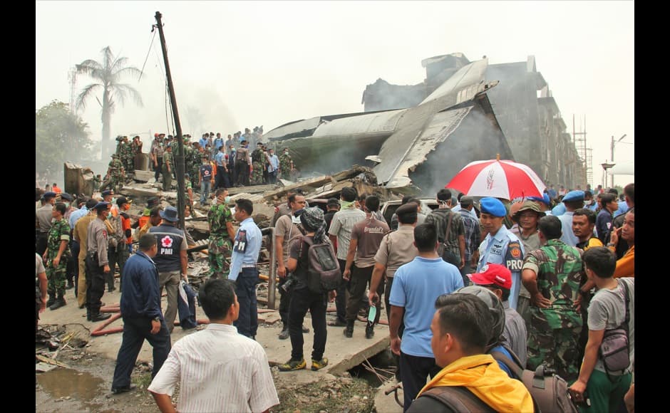 Military personnel inspect the wreckage of an Air Force cargo plane that crashed in Medan, North Sumatra, Indonesia, Tuesday, June 30, 2015. An Indonesian air force Hercules C-130 plane with 12 crew aboard has crashed into a residential neighborhood in the country's third-largest city Medan. (AP Photo/Dedy Zulkifli)