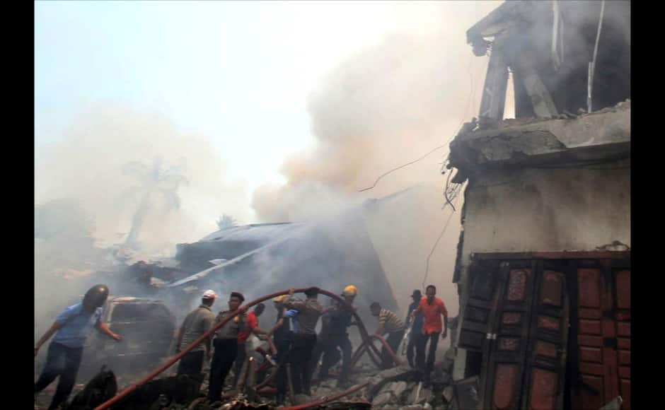 Firefighters and military personnel attempt to extinguish the fire at the site where an Air Force cargo plane crashed in Medan, North Sumatra, Indonesia, Tuesday, June 30, 2015. An Indonesian air force Hercules C-130 plane with 12 crew aboard has crashed into a residential neighborhood in the country's third-largest city Medan. (AP Photo/Gilbert Manullang)