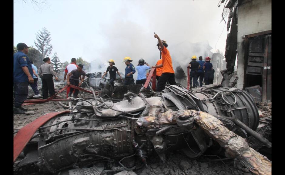 Firefighters and military personnel work at the site where an Air Force cargo plane crashed in Medan, North Sumatra, Indonesia, Tuesday, June 30, 2015. An Indonesian Air Force Hercules C-130 plane with 12 crew aboard has crashed into a residential neighborhood in the country's third-largest city Medan. (AP Photo/Gilbert Manullang)