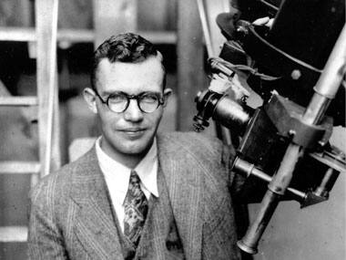 In this 1931 file photo, Clyde Tombaugh poses with the telescope through which he discovered Pluto. AP