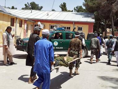 Afghan men carry an injured man to a hospital after a suicide attack at a market in northern Afghanistan. AP