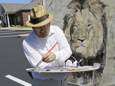 Mark Balma works on a mural of Cecil the lion outside Dr. Walter James Palmer's dental office on Wednesday. AP