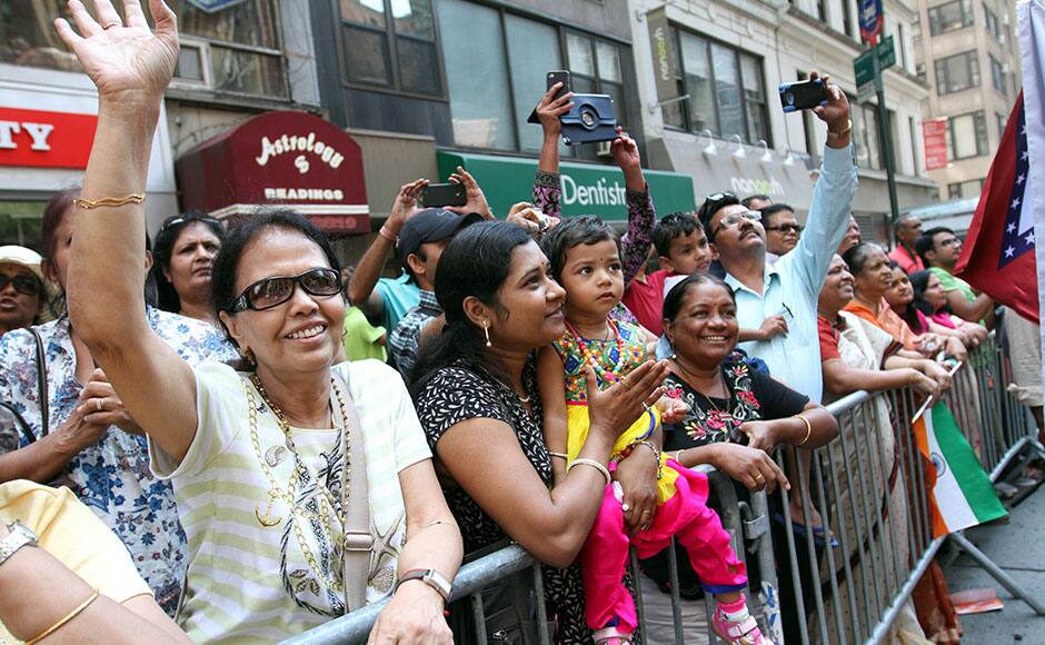 Urvashi Sonis, second from left, holds her child Bhumi Sonis, 2, as they and others watch the India Day Parade go by down New York's Madison Avenue Sunday, Aug. 16, 2015. (AP/Tina Fineberg)