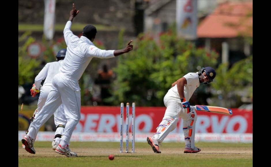 India's Rohit Sharma, right, looks back at his wicket after being bowled out during the fourth day of their first test cricket match against Sri Lanka in Galle, Sri Lanka, Saturday, Aug. 15, 2015. (AP Photo/Eranga Jayawardena)