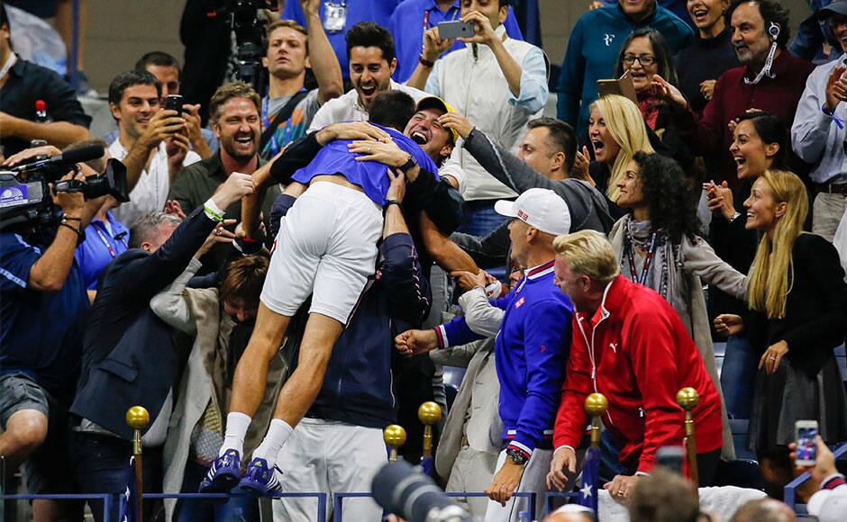 Novak Djokovic of Serbia jumps into his players box to be congratulated by family and friends after defeating Roger Federer of Switzerland in their men's singles final match at the U.S. Open Championships tennis tournament in New York, September 13, 2015. REUTERS