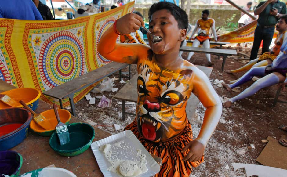 A young artist, eats a meal as he gets his body painted with the likeness of a tiger to perform during the 'Pulikali' or Tiger Dance in Thrissur, Kerala state, India, Monday, Aug. 31, 2015. This folk art festival is held every year in this town to entertain people during the harvest festival ‘Onam’. (AP Photo/Arun Sankar K.)
