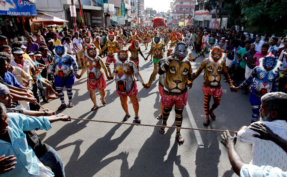 Volunteers hold a rope to keep away the crowd as Indian artists with their bodies painted with the likeness of tigers perform during the 'Pulikali' or Tiger Dance procession in Thrissur, Kerala state, India, Monday, Aug. 31, 2015. This folk art festival is held every year in this town to entertain people during the harvest festival ‘Onam’. (AP Photo/Arun Sankar K.)