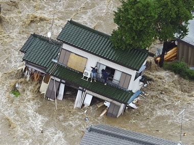 A person inside a submerged house waves to a helicopter. AP