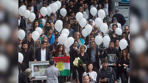 Mourners release white balloons into the sky in Vancouver to honour Syrian boys