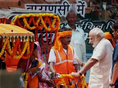 PM Narendra Modi interacts with a beneficiary while giving away e-rickshaws and pedal rickshaws to help impoverished families in Varanasi. PTI