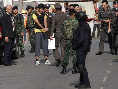 Police officers escort a key suspect in last month’s Bangkok bombing (in yellow shirt) identified by Thai police as Yusufu Mierili, in a re-enactment of his alleged crime. AP 