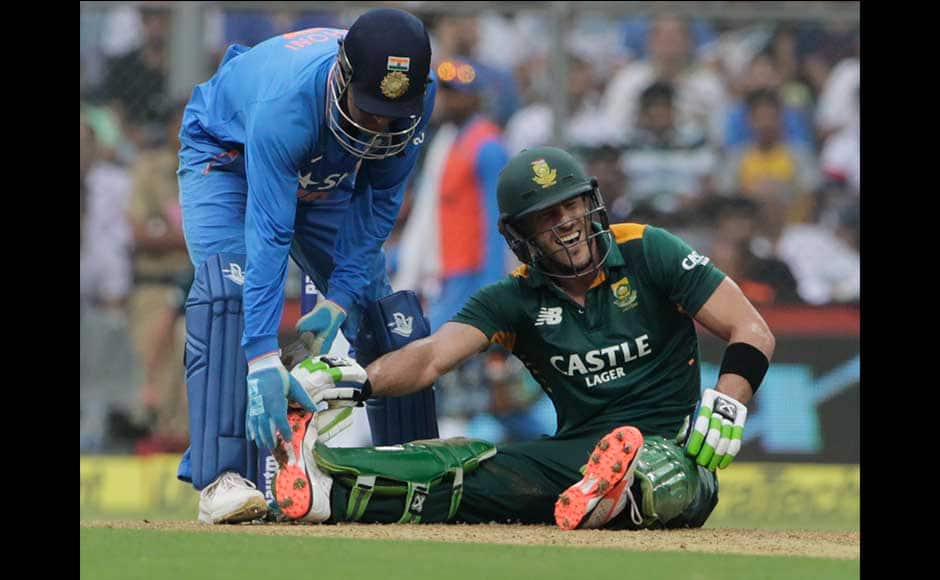 India's captain Mahindra Singh Dhoni, attends to an injured South African batsman Faf du Plessis during the final one-day international cricket match of a five-game series against India in Mumbai, India, Sunday, Oct. 25, 2015. (AP Photo/Rajanish Kakade)