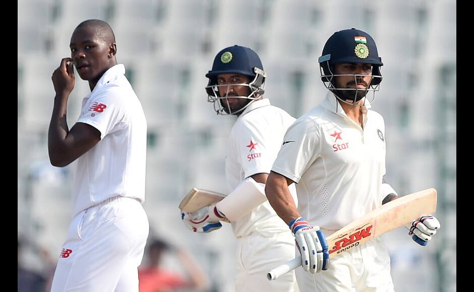 India's Cheteshwar Pujara (C) and Virat Kohli (R) run between wickets as South Africa's Kagiso Rabada looks on on the third day of the first Test match between India and South Africa at The Punjab Cricket Association Stadium in Mohali on November 7, 2015. AFP