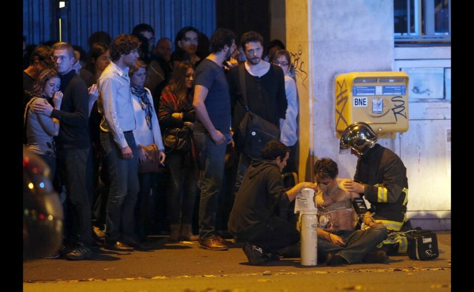 ATTENTION EDITORS - VISUAL COVERAGE OF SCENES OF INJURY OR DEATH A member of the French fire brigade aids an injured individual near the Bataclan concert hall following fatal shootings in Paris, France, November 13, 2015. At least 30 people were killed in attacks in Paris and a hostage situation was under way at a concert hall in the French capital, French media reported on Friday. REUTERS/Christian Hartmann - RTS6VX0