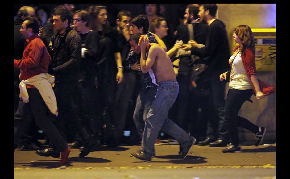ATTENTION EDITORS - VISUAL COVERAGE OF SCENES OF INJURYAn injured man holds his head as people gather near the Bataclan concert hall following fatal shootings in Paris, France, November 13, 2015. At least 30 people were killed in attacks in Paris and a hostage situation was under way at a concert hall in the French capital, French media reported on Friday. REUTERS/Christian Hartmann - RTS6W2R