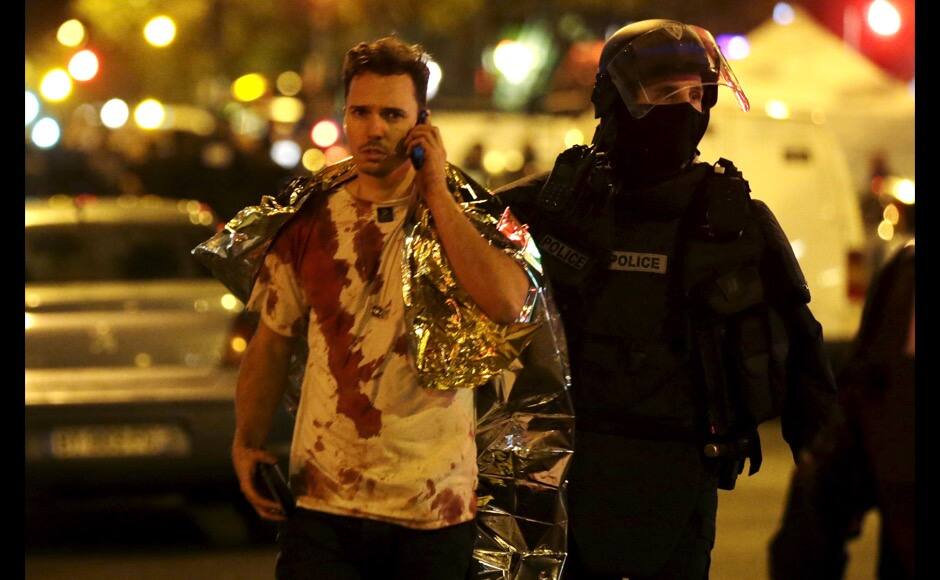 ATTENTION EDITORS - VISUAL COVERAGE OF SCENES OF INJURY A French policeman assists a blood-covered victim near the Bataclan concert hall following attacks in Paris, France, November 14, 2015. Gunmen and bombers attacked busy restaurants, bars and a concert hall at locations around Paris on Friday evening, killing dozens of people in what a shaken French President described as an unprecedented terrorist attack REUTERS/Philippe Wojazer - RTS6X0S