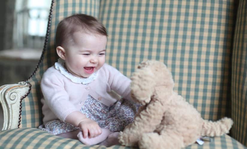 Princess Charlotte giggles as she plays with her stuffed puppy. AFP