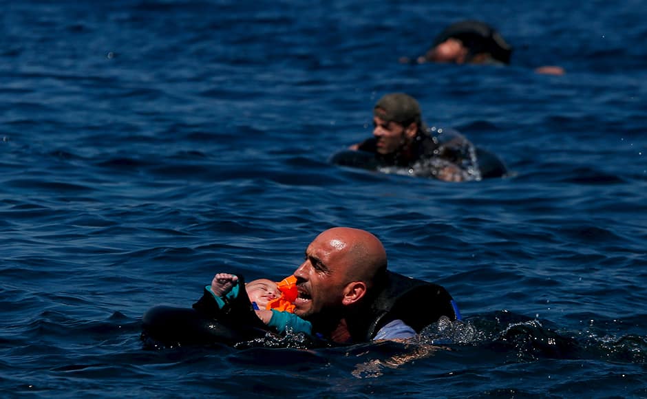 A Syrian refugee holding a baby swims towards the Greek island of Lesbos, September 12, 2015. Alkis Konstantinidis: Another inflatable boat packed with dozens of migrants and refugees heading towards the shore. That’s what I noticed in the distance. The sea was calm and they were cheering on the dinghy. Suddenly, some 200 metres away, the rear of the boat deflated for no obvious reason, and people started falling into the sea. Screams replaced cheers as they frantically tried to stay afloat on life tubes, or by clinging on to the boat. Those who could swim tried to help those who couldn’t. As this dramatic scene unfolded and people drifted away from each other, the biggest challenge was to capture as many of the different scenes as I could. There were people falling overboard; two men trying to keep their friend afloat; a man still on the boat lifting his child in the air; another man, nearing collapse from exhaustion, swimming towards the shore; volunteers rushing towards the boat. In this hectic moment, one man, tense and yelling really loudly, caught my eye so I shot some frames. Later, as he tried to catch his breath on the beach, I asked him where he was from. “Syria,