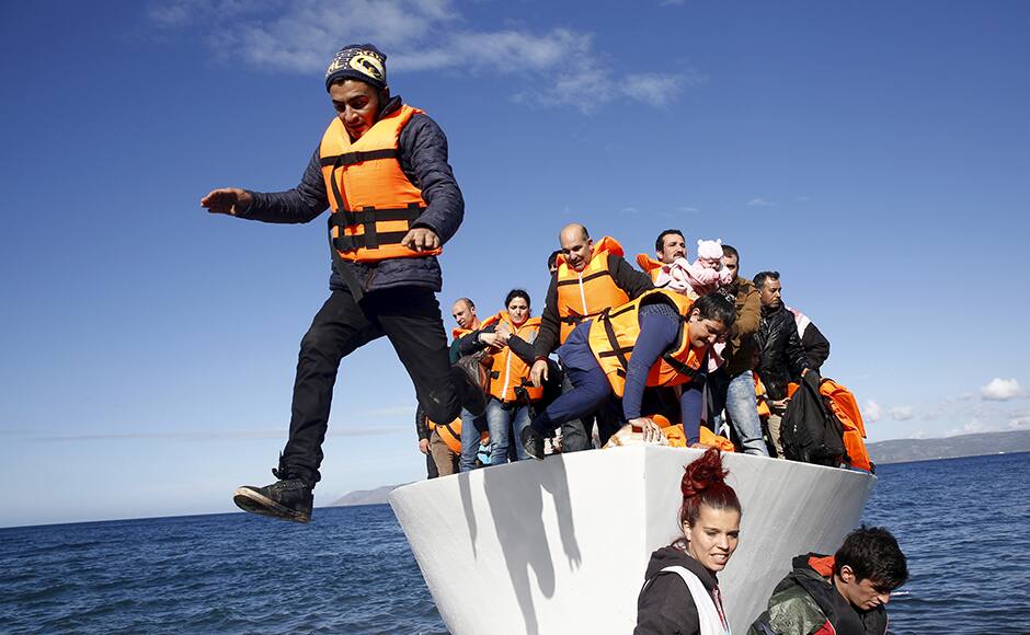 .Refugees and migrants jump off a boat as they arrive on the Greek island of Lesbos, November 26, 2015. REUTERS/Giorgos Moutafis 