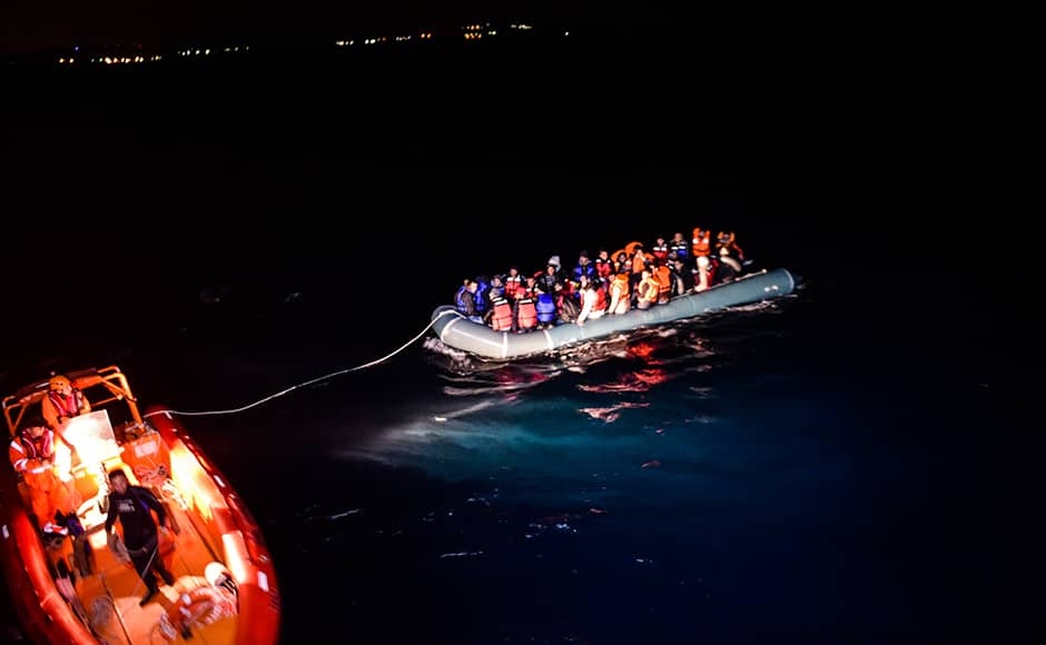 Members of the Turkish Coast Guard rescue Syrian migrants aboard an inflatable dinghy, attempting to reach the Greek island of Chios, on the Agean Sea near Izmir in the night of December 9 to December 10, 2015. More than 886,000 migrants have arrived in Europe by sea so far this year, according to the latest UN figures. BULENT KILIC / AFP 