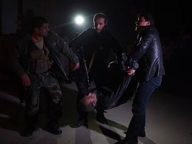 Afghan security personnel carry a wounded man at the site of an attack on the Spanish embassy compound in Kabul. AFP 