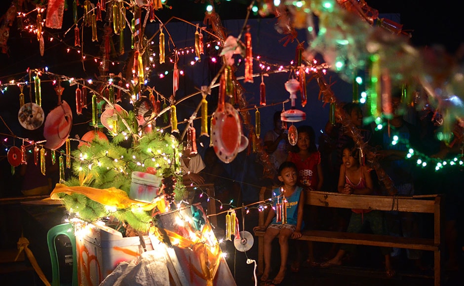 TACLOBAN,-LEYTE,-PHILIPPINES---DECEMBER-24-Survivors-cheer-after-a-Christmas-tree-they-built-using-storm-debris-is-lit-up-on-Christmas-eve-on-December-24,-2013-in-Tacloban,-Leyte,-Philippines TACLOBAN,-LEYTE,-PHILIPPINES---DECEMBER-24-Survivors-cheer-after-a-Christmas-tree-they-built-using-storm-debris-is-lit-up-on-Christmas-eve-on-December-24,-2013-in-Tacloban,-Leyte,-Philippines
