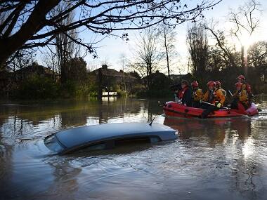 Members of the emergency services paddle down Huntington Road past a submerged parked car after the adjacent River Foss burst it's banks in York. AFP 