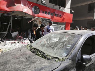 People look at a damaged vehicle outside a Vodafone branch following a blast, in Cairo People look at a damaged vehicle outside a Vodafone branch following a blast, in Cairo