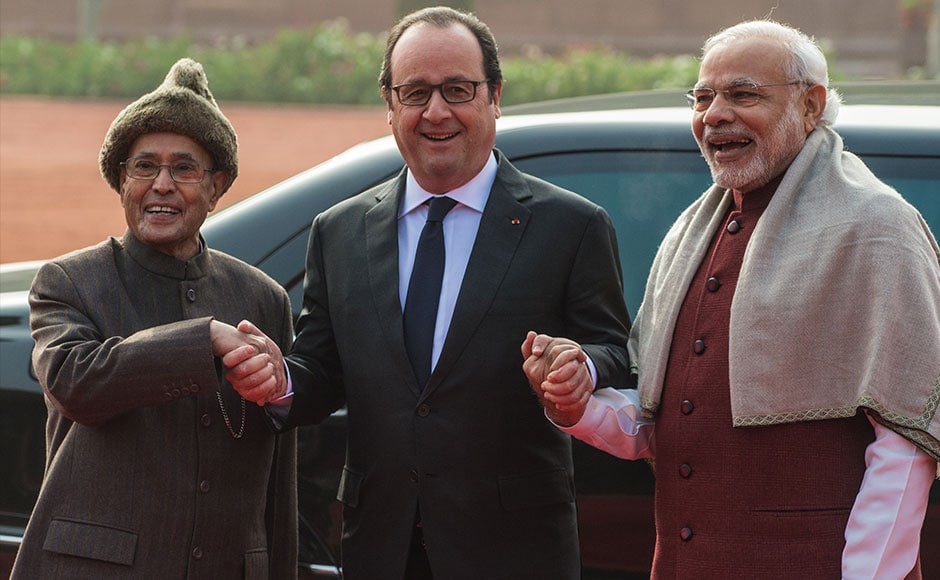 French President Francois Hollande smiles as he holds the hands of Indian President Pranab Mukherjee (L) and Indian Prime Minister Narendra Modi (R) as they pose for a photograph at an official welcoming ceremony in New Delhi on January 25, 2016. After beginning a three-day visit to India in the northern city of Chandigarh on January 24, French President Francois Hollande has headed to the capital New Delhi to make common cause with India's Prime Minister Narendra Modi on issues such as combating Islamist extremists and climate change. AFP PHOTO /ROBERTO SCHMIDT