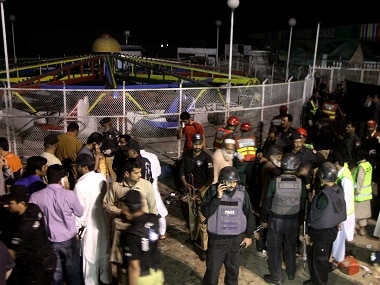 Pakistani police officers and rescue workers gather at the site of bomb explosion in a park in Lahore on Sunday. AP