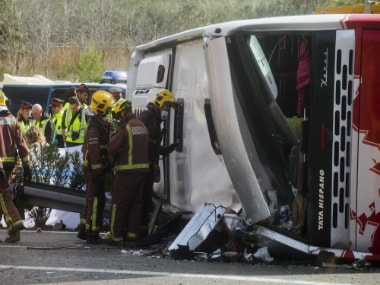 Emergency services personnel stand at the scene of a bus accident crashed on the AP7 highway that links Spain with France on Sunday. AP