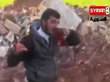 An image grab taken on May 15, 2013 from an undated video uploaded on YouTube allegedly shows Khaled al-Hamad, a rebel fighter known as Abu Sakkar and commander of the Omar al-Faruq brigade in Homs, Syria, holding the heart (L) and the liver (R) of a Syrian government soldier after cutting it out from his dead body. AFP