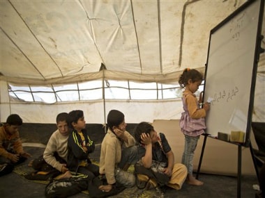 Syrian refugee Ghufran Ahmad, 5, writes on a board while she and other children attend a class at a makeshift school set up in a tent at an informal tented settlement in the Jordan Valley, Jordan, Thursday, March 31, 2016. AP