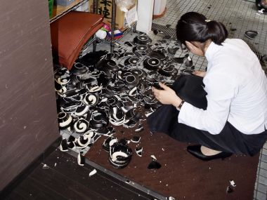 A woman collects fallen dishes at a restaurant after an earthquake in Kumamoto, southern Japan on Thursday. AP