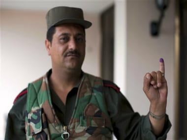 A Syrian policeman poses for a photograph showing his inked finger after voting outside a polling station during the parliamentary election in Damascus, Syria, Wednesday. AP