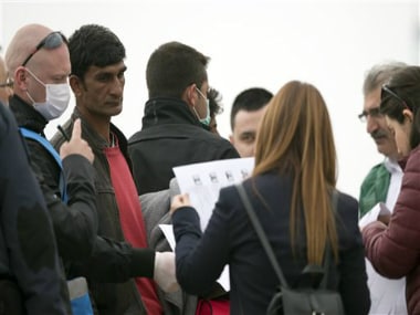 A Frontex staff member and Turkish Interior Ministry employees check documents of a Pakistani migrant, second from left, before getting on a ferry for Turkey in the port of Mytilini of the Greek island of Lesbos, Friday, April 8, 2016. AP