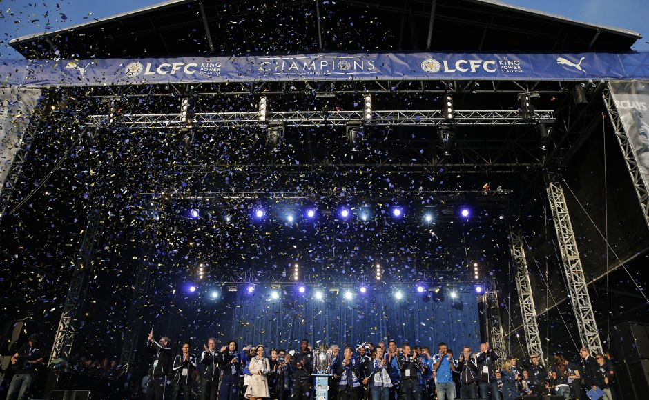 Leicester City players on stage alongside the Premier league trophy. AFP PHOTO / ADRIAN DENNIS