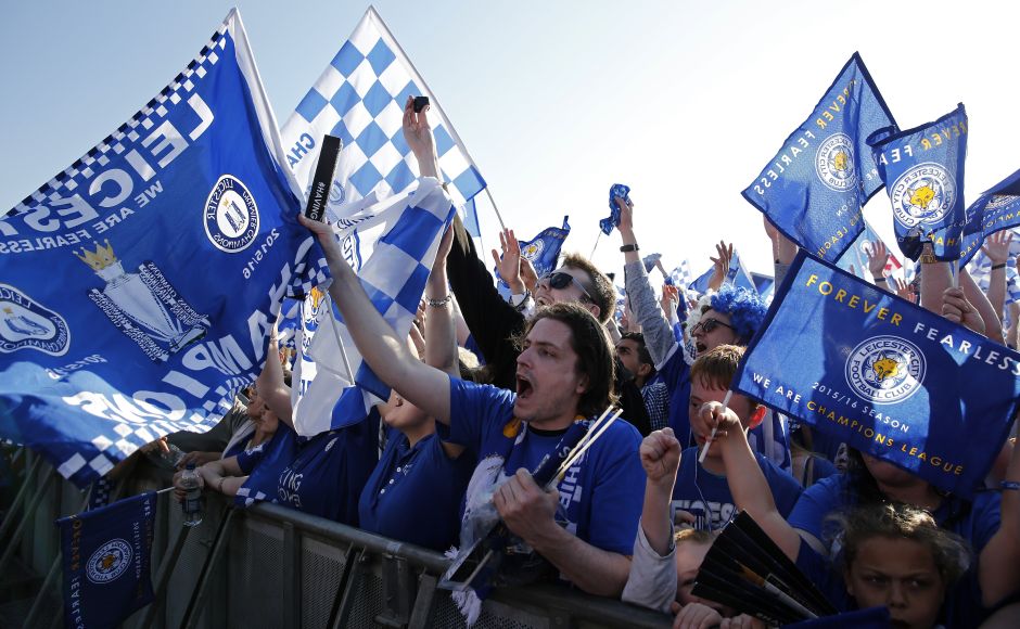 Leicester City fans wave banners as they wait to see the players pose with the Premier League trophy. AFP / ADRIAN DENNIS