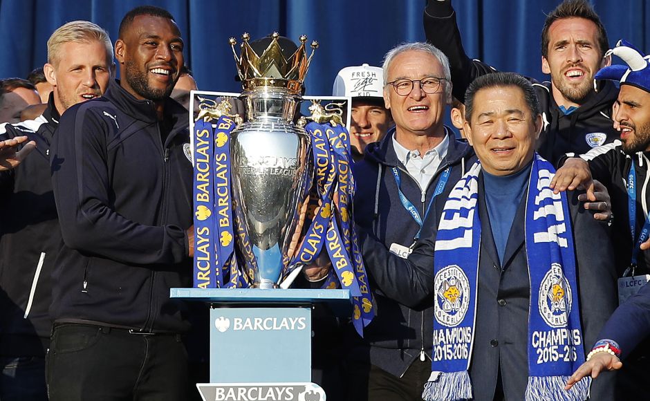Leicester City's Thai owner Vichai Srivaddhanaprabha, Claudio Ranieri and Wes Morgan stand with the trophy on stage Victoria Park after the open-bus parade. AFP PHOTO / ADRIAN DENNIS