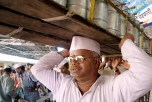 Sopan Laxman More, President of Mumbai tiffin box suppliers association, carries a tiffin carrier at a railway station in Bombay April 6, 2005. Two 