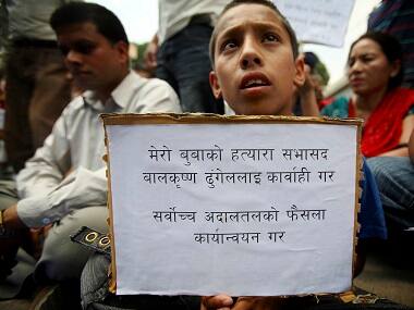 Bikash Shrestha, 13, who lost his father Bhuvan Shrestha during the decade-long civil conflict between the then government and the Maoists, holds a placard while participating during a sit in protest demanding for justice near the Singha Durbar office complex that houses the prime minister's office and other ministries in Kathmandu on 6 June, 2011. The placard reads, 