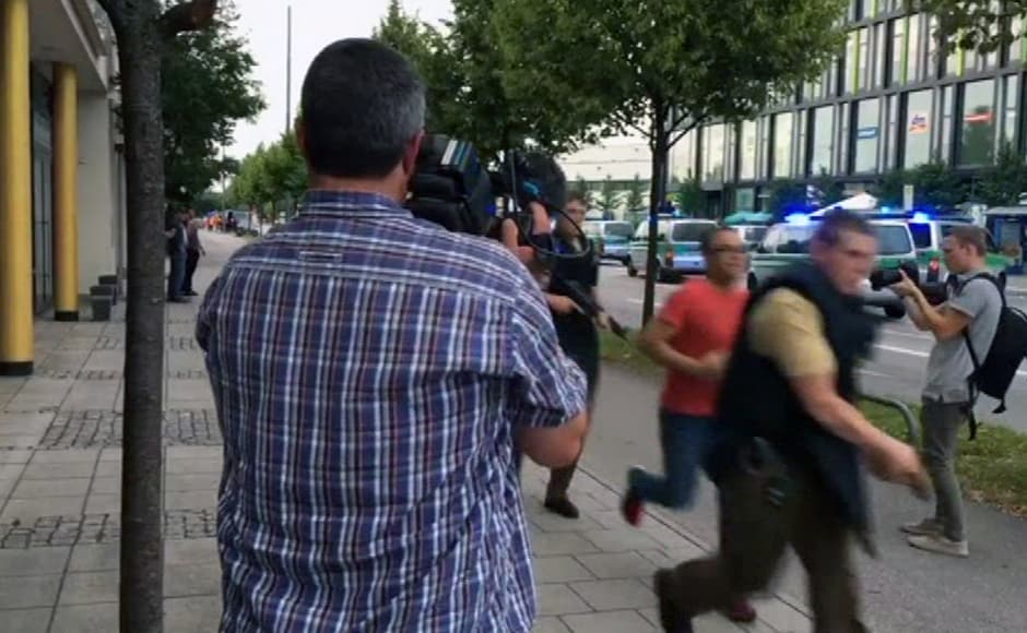 Armed police responding to the shooting move past onlooking media. Armed police responding to the shooting move past onlooking media.