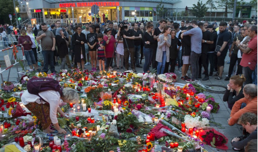 Munich new2_People gather to mourn with flower tributes near to the Olympia shopping center where a shooting took place leaving nine people dead the day before in Munich on Saturday. AP