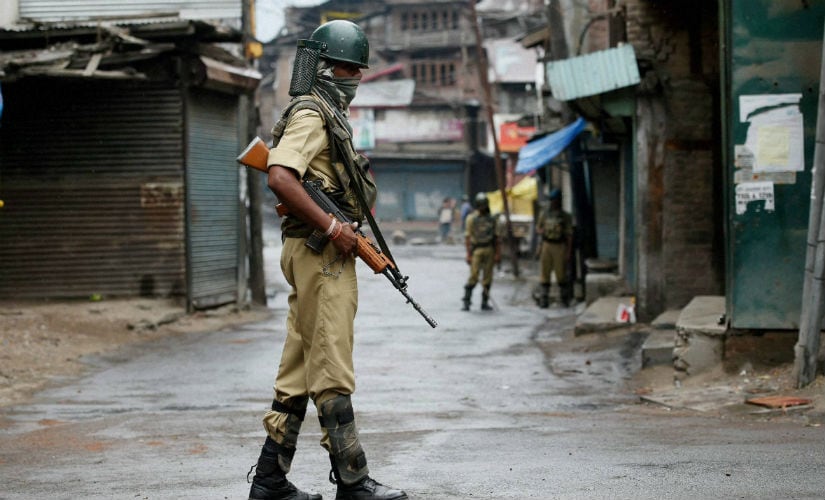 Police guards a deserted street during the curfew in the state. PTI