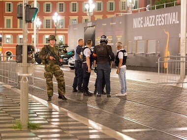 Police officers and a soldier stand by the sealed off area of an attack after a truck drove on to the sidewalk and plowed through a crowd of revelers who'd gathered to watch the fireworks in the French resort city of Nice on Thursday night. AP