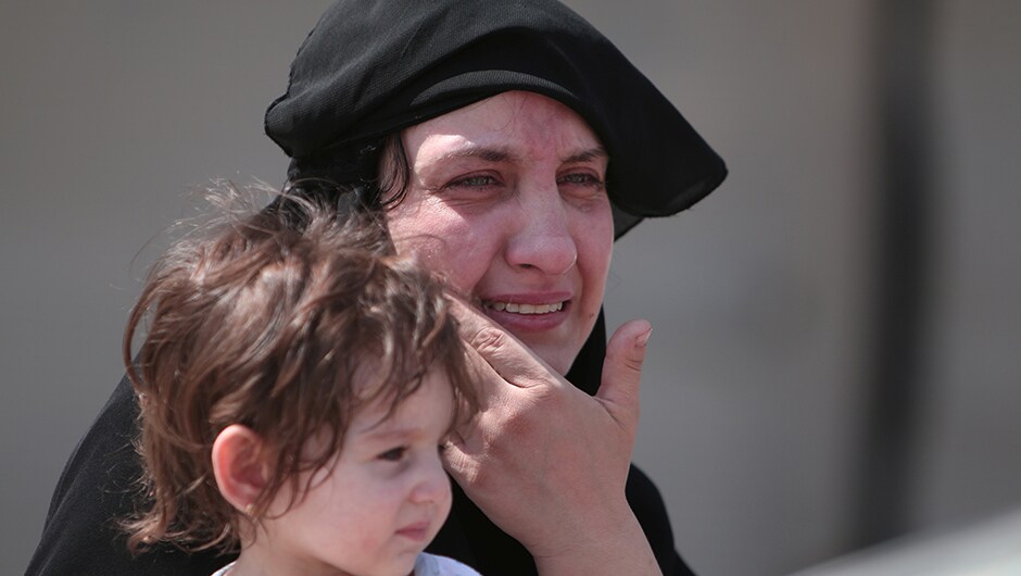 A woman sits with her child after they were evacuated by the SDF fighters from Manbij. A woman sits with her child after they were evacuated by the SDF fighters from Manbij.