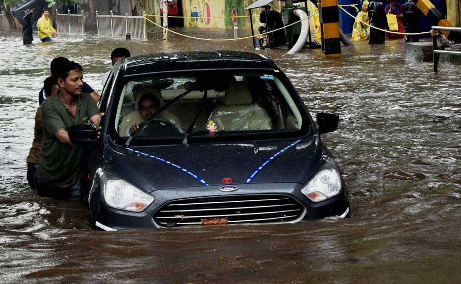 People pushing car through flooded street during heavy rains in Mumbai on Friday. Potholes and heavy waterlogging became a major nuisance for people. PTI People pushing car through flooded street during heavy rains in Mumbai on Friday. Potholes and heavy waterlogging became a major nuisance for people. PTI