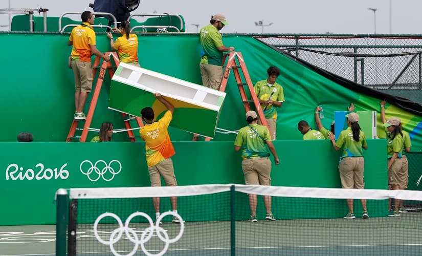 Volunteers work to repair wind damage on a court during the tennis competition at the 2016 Summer Olympics in Rio de Janeiro, Brazil, Sunday, Aug. 7, 2016. Because of wind that reached 25 mph (40 kph), the start of Sunday's play in the Rio de Janeiro Olympic tennis tournament was delayed on all courts except the main stadium, some matches started about 2 hours late.(AP Photo/Vadim Ghirda)