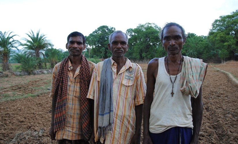Julian Pradhan (extreme right), with his two brothers on the land they own. Firstpost/Rahul Pandita